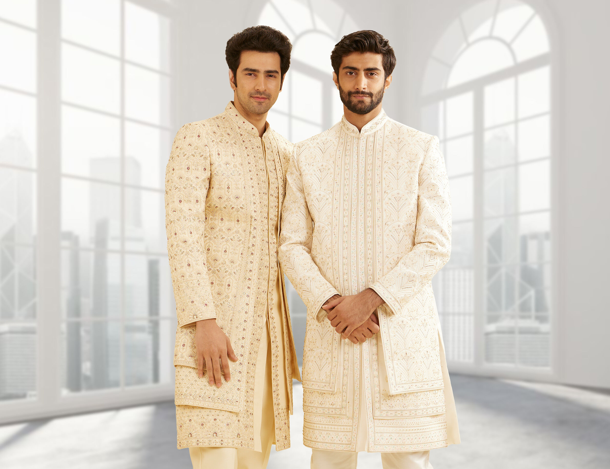 Two men in cream-colored sherwanis, one with a side-cut design and the other with intricate embroidery